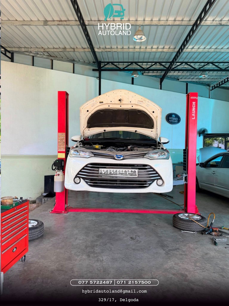 White hybrid hatchback raised on Launch two-post lift