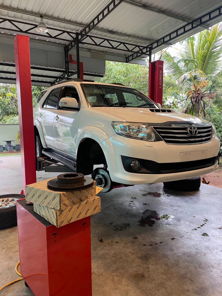 White Toyota SUV on lift for brake service with genuine parts visible