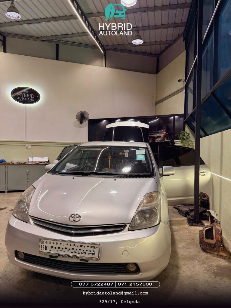 Silver Toyota Prius with driver door open in the service bay