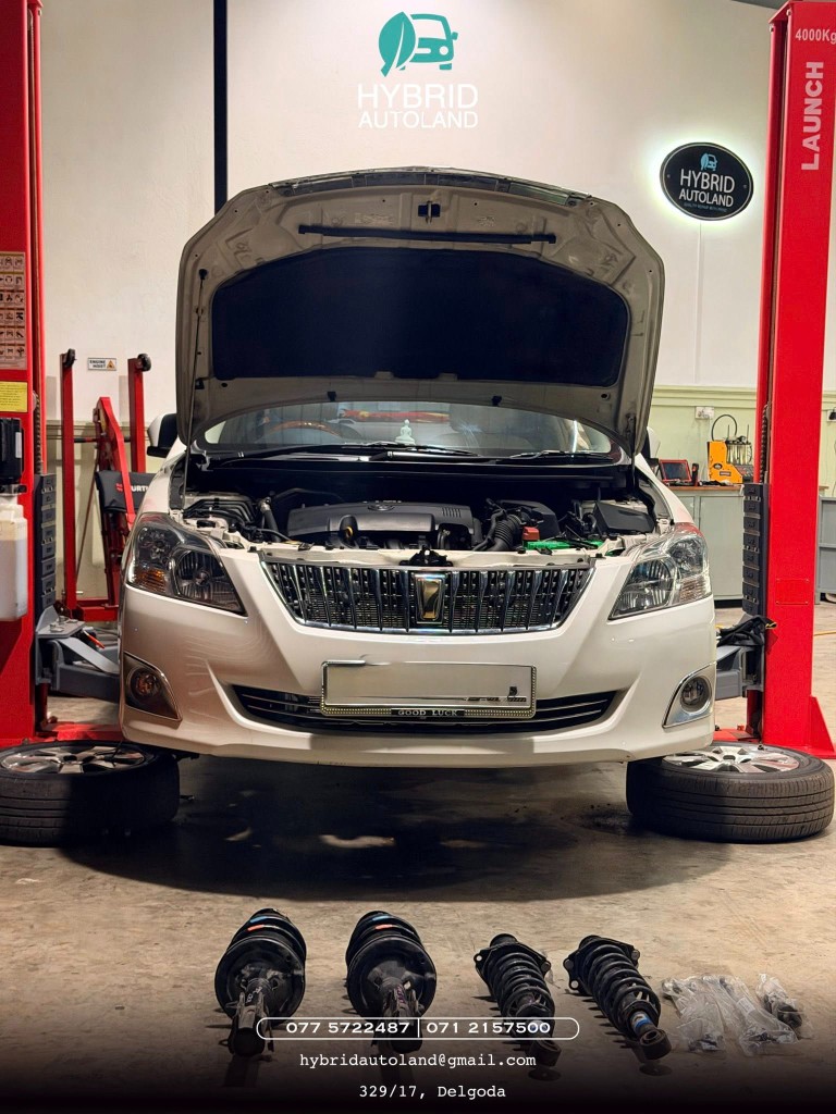 White sedan with struts laid out for suspension service between lifts