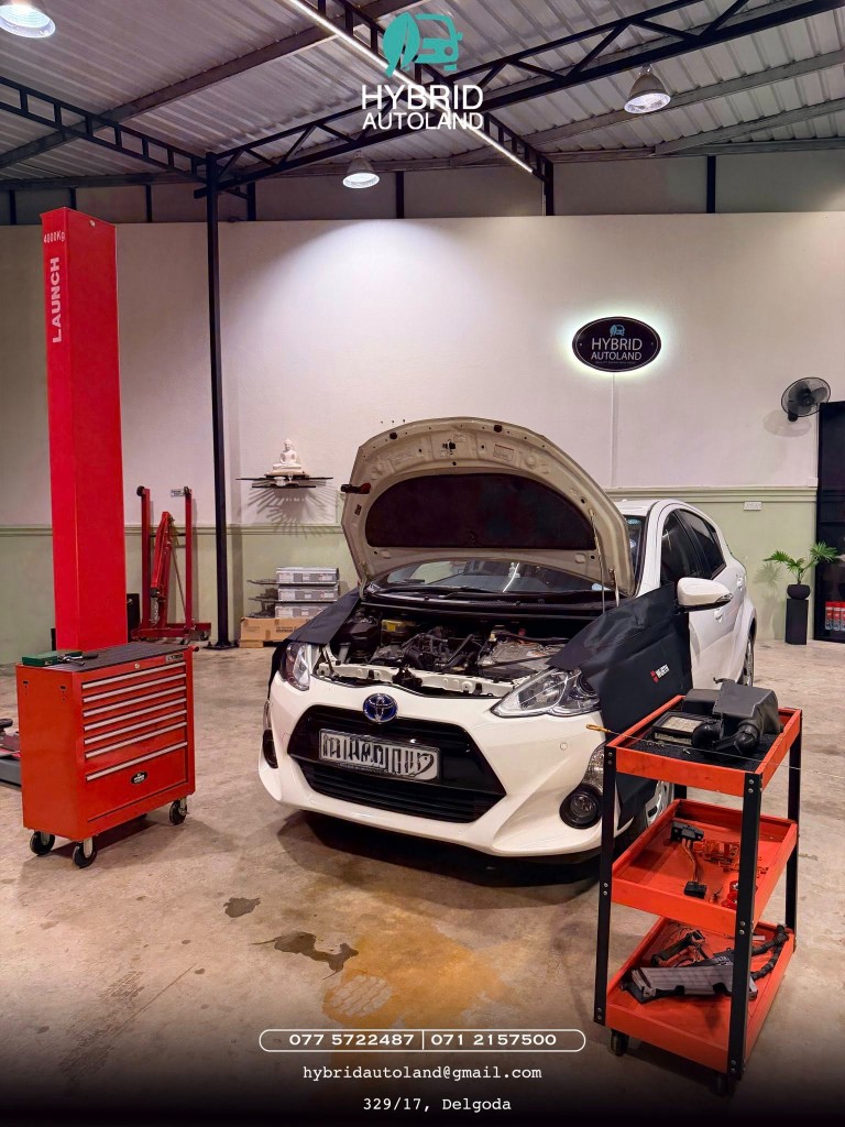 White Toyota Aqua hybrid with hood open in the bay