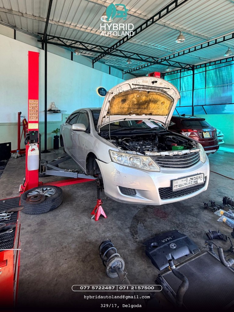 Silver Toyota sedan raised on a two-post hydraulic lift with hood open