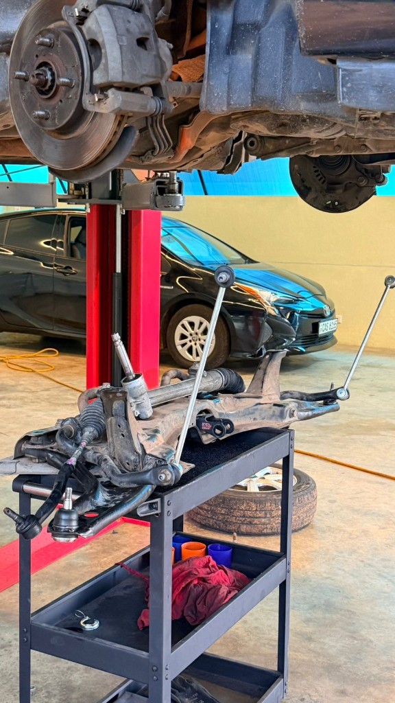 Steering rack assembly on a cart beneath a vehicle raised on the lift